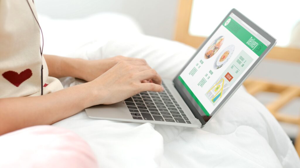 Asian woman order food online with laptop on bed at home